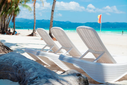 A couple of lawn chairs sitting on top of a sandy beach